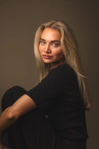 blonde frau schwarz angezogen, sitzt auf dem boden